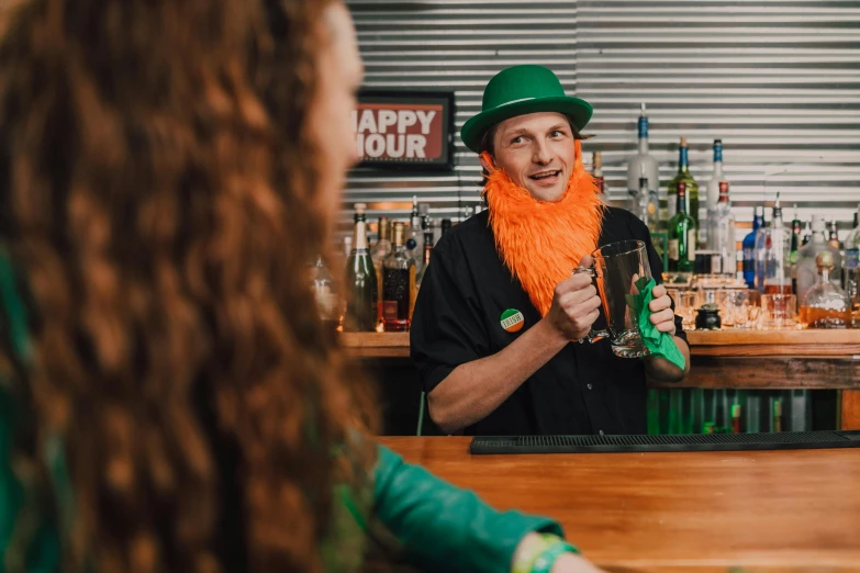 a man with an orange beard sitting at a bar, green and orange theme, cheers, the rad hatter, aussie baristas