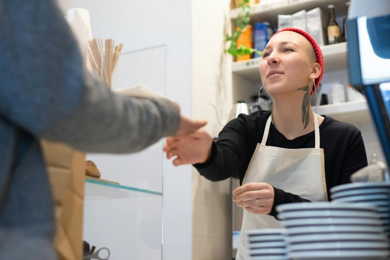 a woman shaking hands with a man in a kitchen, pexels contest winner, arbeitsrat für kunst, aussie baristas, starbucks aprons and visors, non-binary, getting groceries