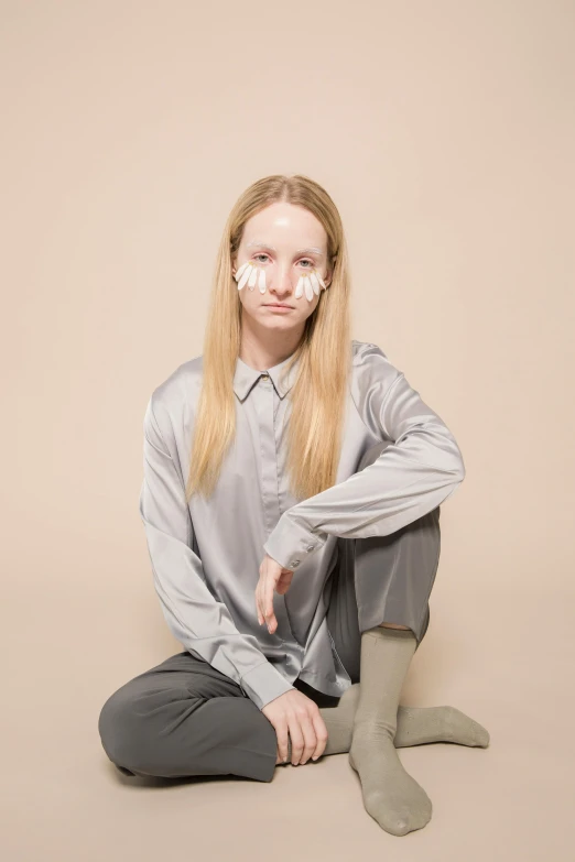 a woman sitting on the ground with her hands on her knees, an album cover, inspired by Anna Füssli, trending on reddit, realism, marble white complexion, collared shirt, silver，ivory, nonbinary model