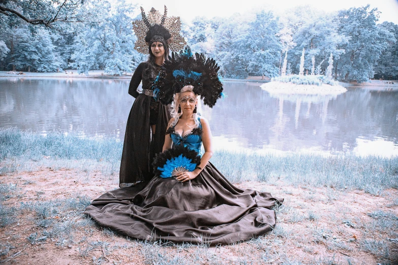 a couple of women standing next to each other, an album cover, by Elena Guro, pexels contest winner, renaissance, dress made of feathers, black and cyan color scheme, jeweled costume, photography of enchanted forest