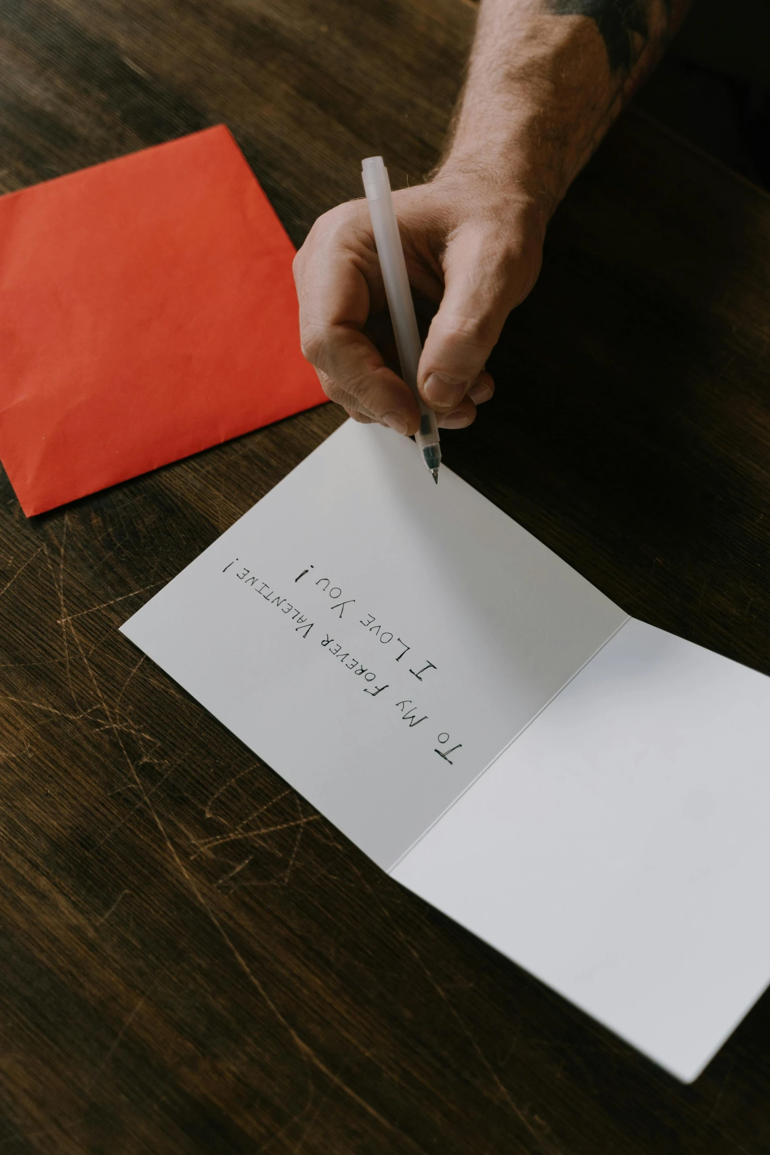 a person holding a pen and writing on a piece of paper, greeting card