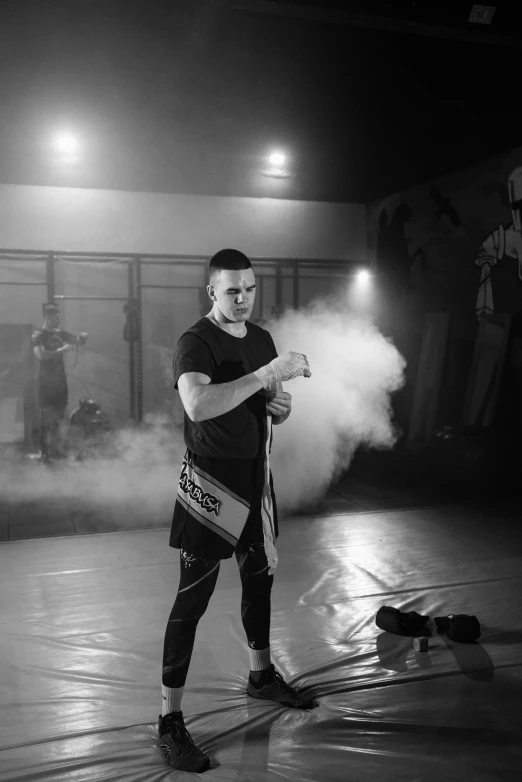 a man standing on top of a tennis court holding a tennis racquet, a black and white photo, inspired by Ma Quan, pexels contest winner, heroic muay thai stance pose, smoke filled room, ernest khalimov body, performing a music video