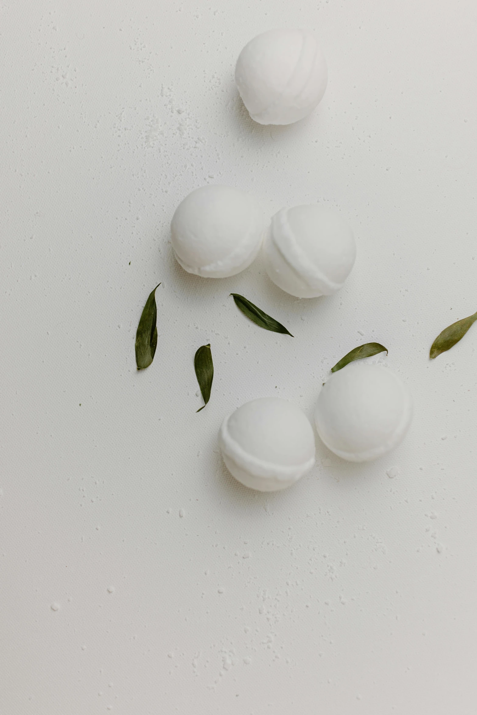 a bunch of white balls sitting on top of a table, by Jessie Algie, trending on pexels, photoshoot for skincare brand, matte white background, leafs, bath