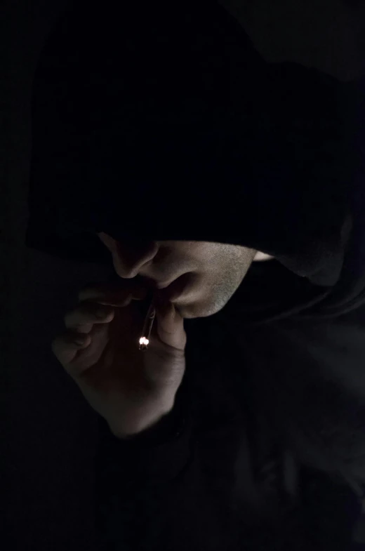 a man in a hoodie looking at a cell phone, by Alessandro Allori, pexels contest winner, hyperrealism, lips on cigarette, eerie person silhouette, nug pic, on dark paper