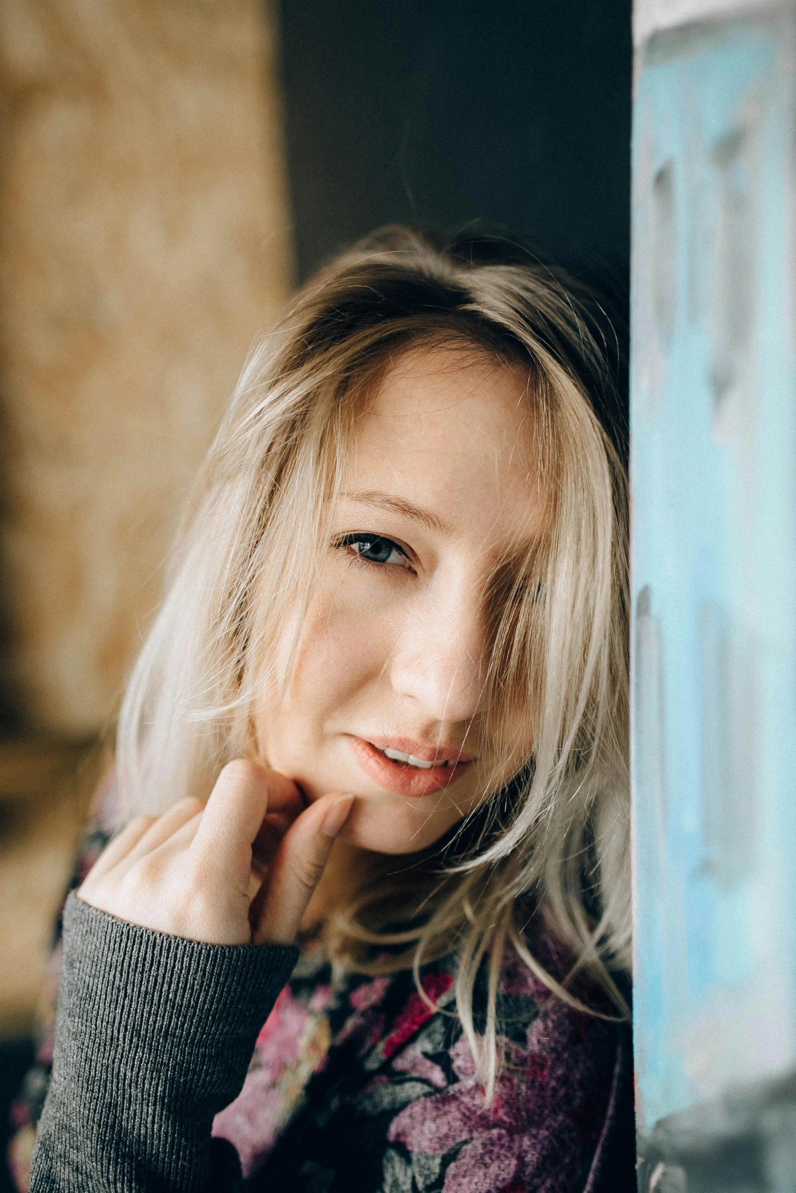 a woman leaning against a wall with her hand on her chin, a picture, tachisme, blonde hair and blue eyes, portrait featured on unsplash, indoor picture, avatar image