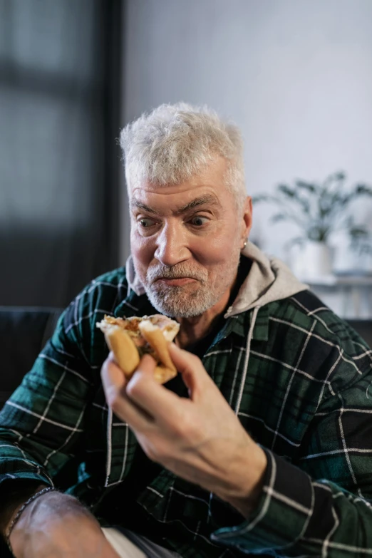 a man sitting on a couch eating a hot dog, a picture, shutterstock, dark grey haired man, eating garlic bread, headshot, instagram post