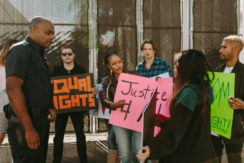 a group of people holding signs in front of a building, by Julia Pishtar, pexels contest winner, courtroom scene, qiyana, stood in a cell, tyler west