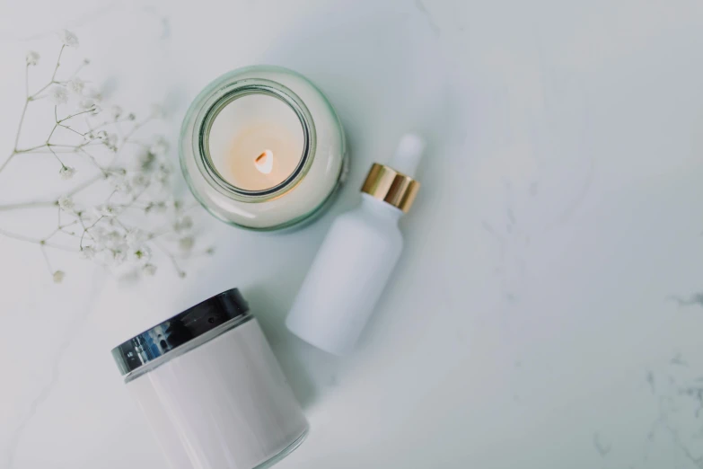 a candle sitting on top of a table next to a jar of cream, by Emma Andijewska, trending on pexels, minimalism, white powder makeup, various items, bath, white background