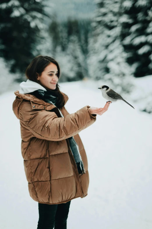 a woman standing in the snow holding a bird, pexels contest winner, symbolism, handsome girl, happy friend, 1 2 9 7, premium quality