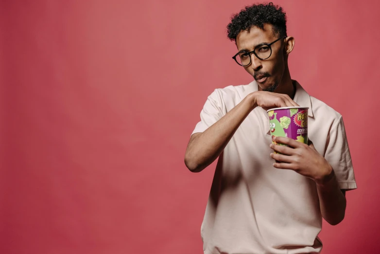 a man in glasses holding a cup of ice cream, an album cover, inspired by Ismail Gulgee, trending on pexels, model pose, mixed race, thin young male, paper cup