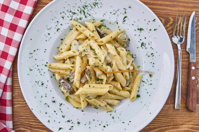 a white plate topped with pasta on top of a wooden table, 5 7 9, order, mushroom, thumbnail