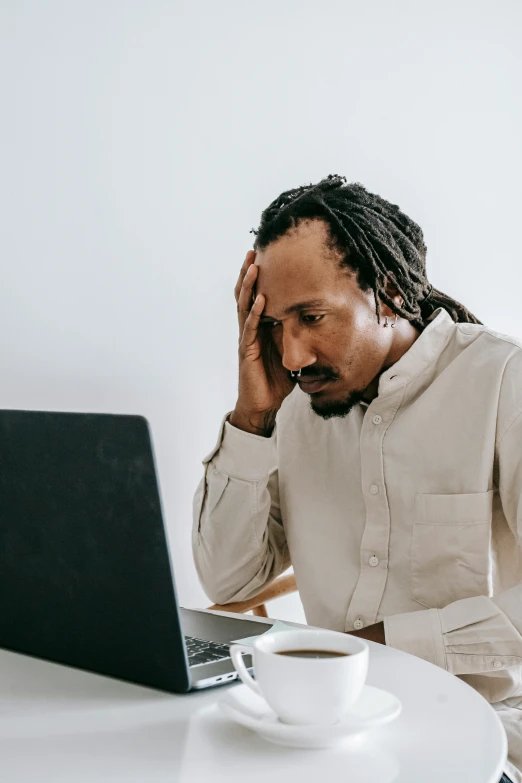 a man sitting at a table with a laptop and a cup of coffee, trending on pexels, people crying, dreads, in an office, thumbnail