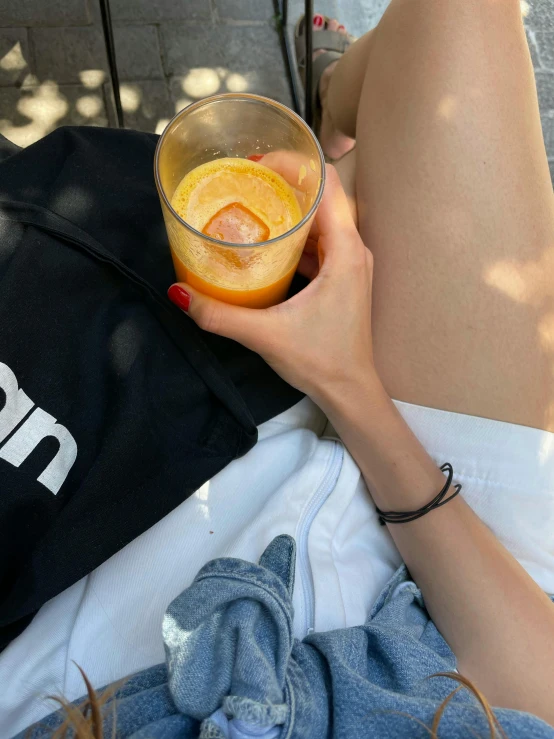 a woman laying on the ground with a glass of orange juice, by Niko Henrichon, trending on unsplash, realism, neon hand sports bracelet, wearing black shorts, 🎀 🧟 🍓 🧚, casually dressed