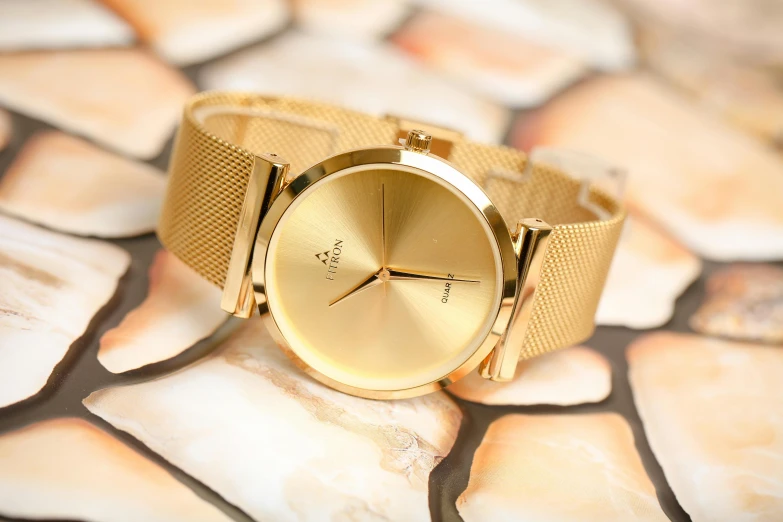 a close up of a watch on a stone surface, a portrait, by Julia Pishtar, trending on unsplash, relaxed. gold background, gold suit, photo taken with provia, hansa yellow