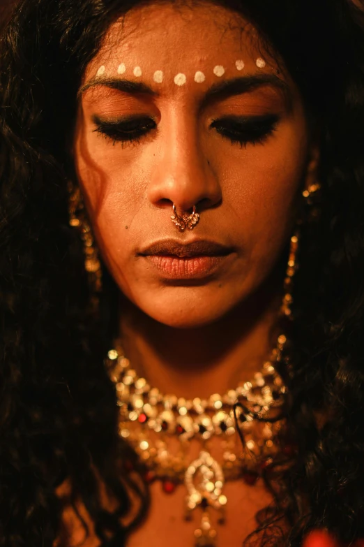 a close up of a woman with piercings on her face, an album cover, trending on pexels, renaissance, hindu stages of meditation, dimly lit scene, black jewelry, lgbtq