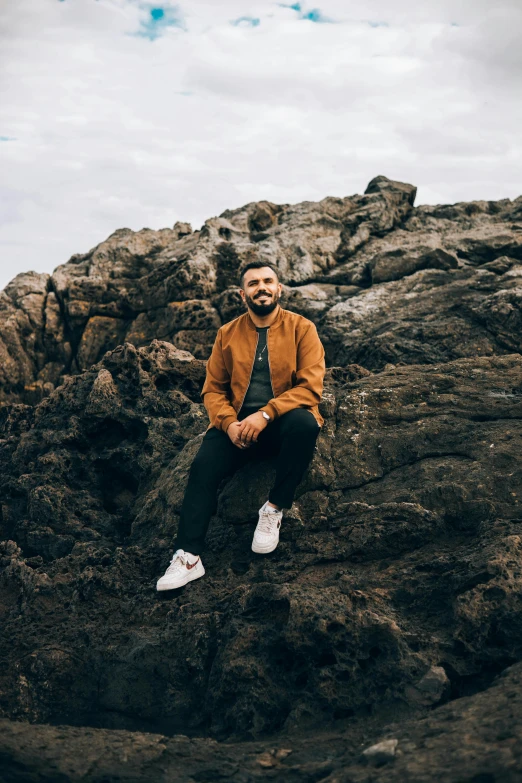 a man sitting on top of a large rock, an album cover, pexels contest winner, zachary corzine, slightly smiling, coastal, bearded