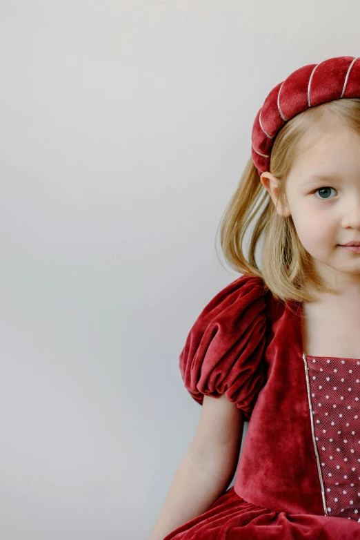 a little girl wearing a red dress and a red hat, an album cover, inspired by Kate Greenaway, pexels, renaissance, dressed in velvet, full product shot, raspberry, corduroy