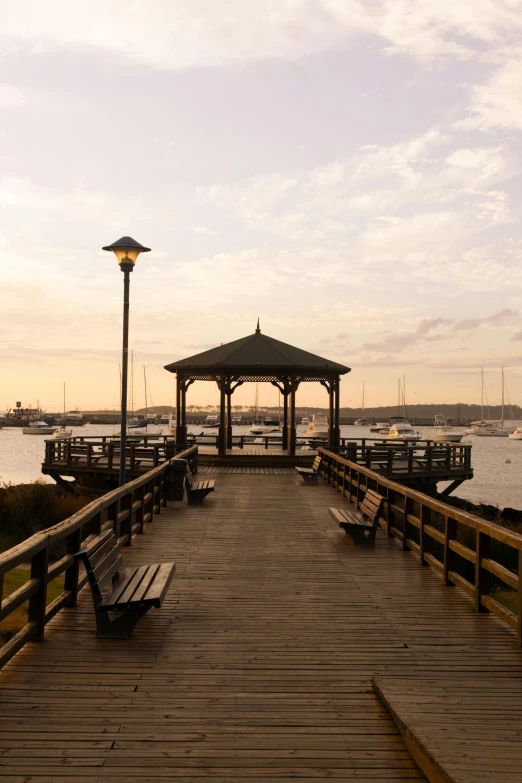 a gazebo sitting on top of a wooden pier next to a body of water, by Dave Melvin, peaceful evening harbor, manly, benches, 8 k -