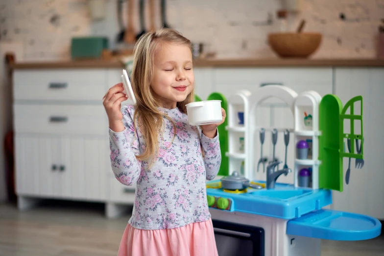 a little girl that is drinking out of a cup, inspired by Elsie Henderson, dau-al-set, in a kitchen, activity play centre, blue, full product shot