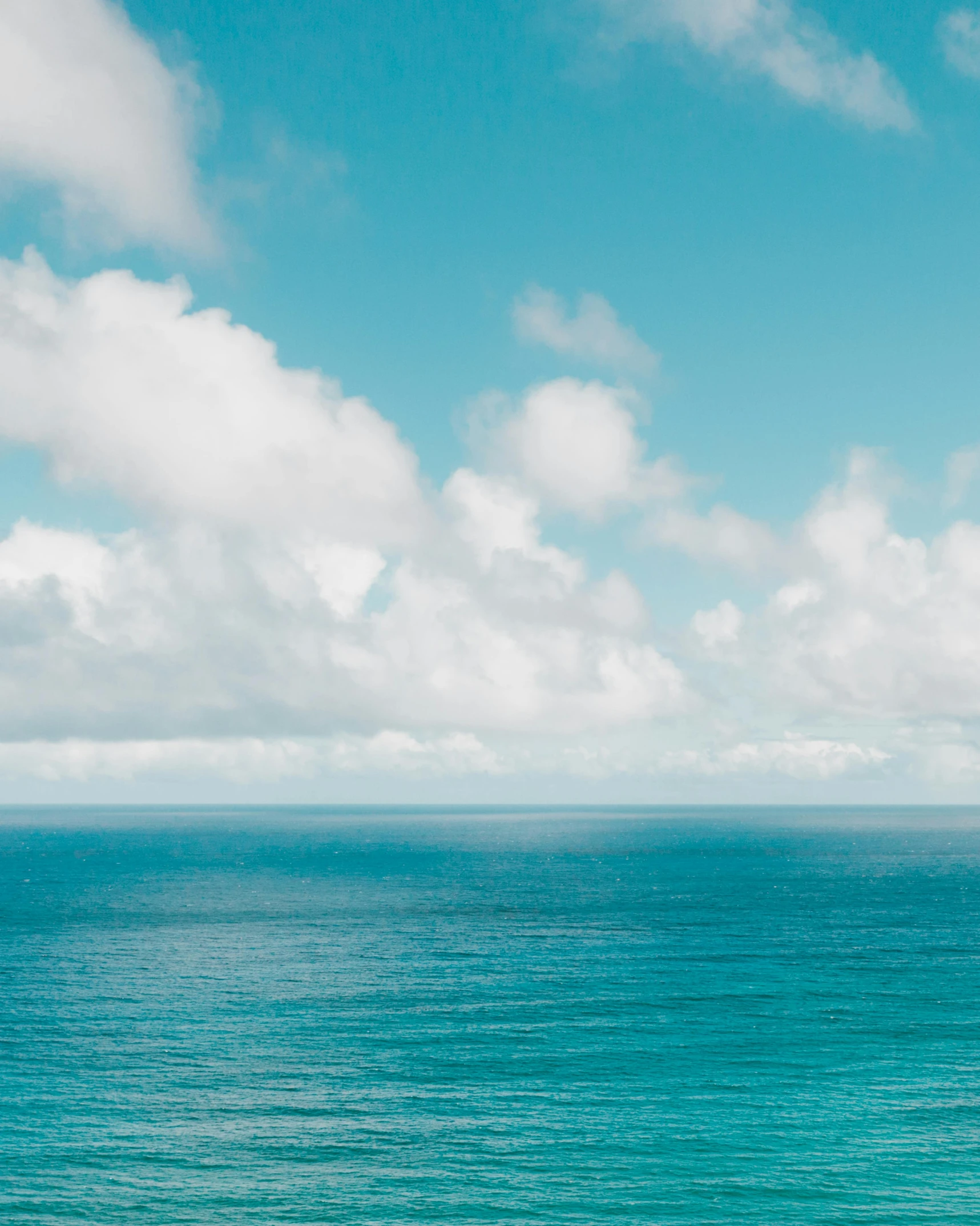 a man riding a surfboard on top of a sandy beach, trending on unsplash, minimalism, panorama view of the sky, azores, cumulus, cerulean