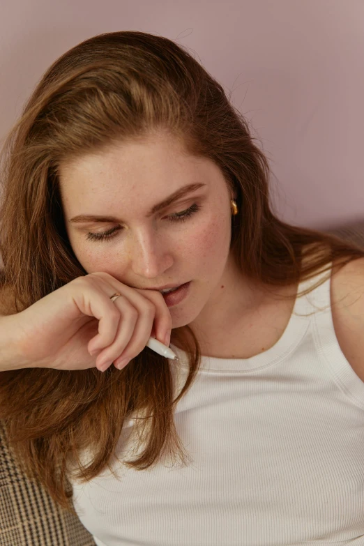 a woman sitting on a couch smoking a cigarette, inspired by Elsa Bleda, trending on pexels, renaissance, exhausted face close up, someone sits in bed, on a pale background, girl with brown hair