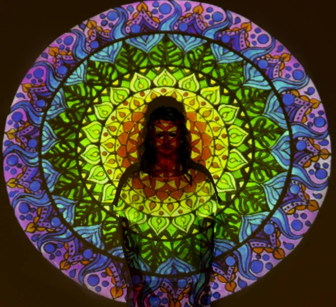 a woman standing in front of a stained glass window, a hologram, inspired by Alex Grey, psychedelic art, neon madhubani, round-cropped, padmasana, projection design installation