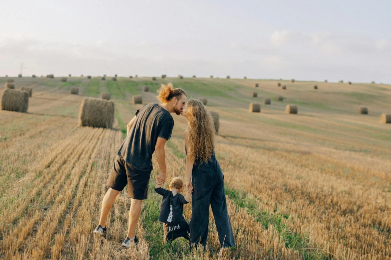 a man and a woman kissing in a field with hay bales, by Emma Andijewska, pexels contest winner, portrait of family of three, 15081959 21121991 01012000 4k, australian, wide full body