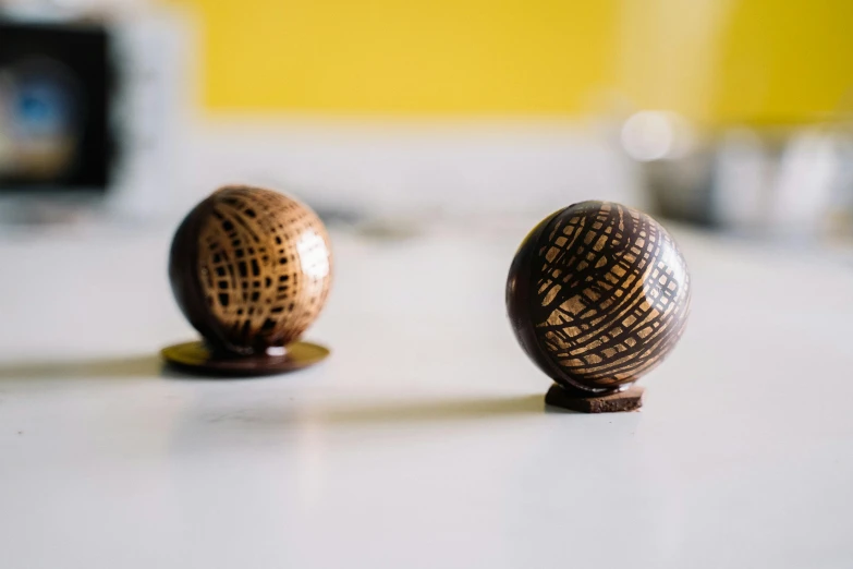 a couple of wooden balls sitting on top of a table, inspired by Ásgrímur Jónsson, unsplash, fully chocolate, gold striated swirling finish, small gadget, crosshatch