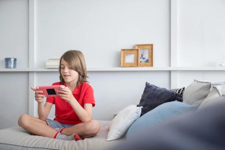 a little girl sitting on a couch playing a video game, pexels contest winner, happening, looking at his phone, soft grey and red natural light, photograph of 3d ios room, teenager hangout spot