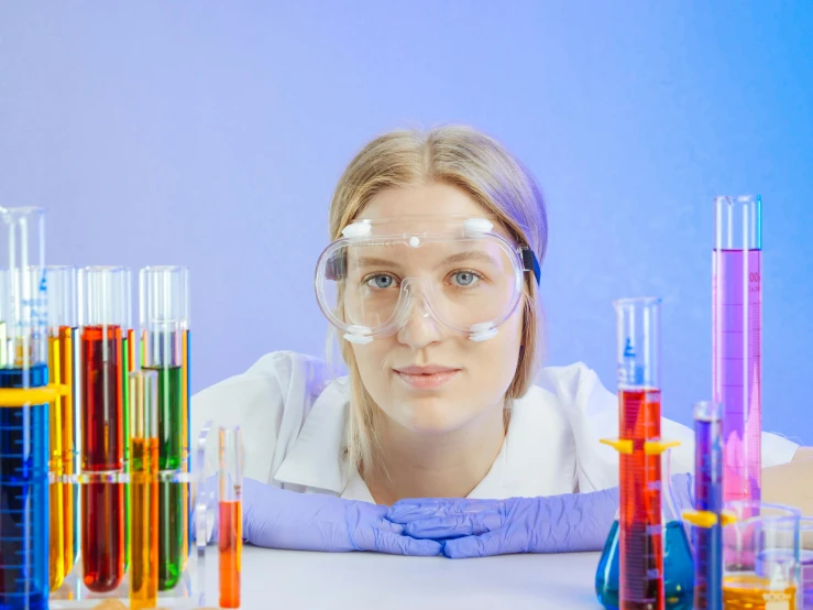 a woman sitting at a table in front of a bunch of test tubes, trending on pexels, russian academic, goggles, girl wearing uniform, portrait photo of a backdrop