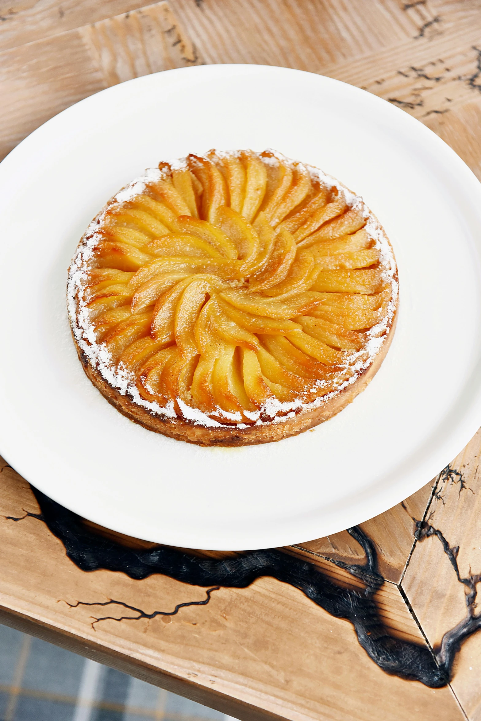 a white plate topped with a pastry on top of a wooden table, inspired by Richmond Barthé, baroque, apple, 4l, handcrafted, back