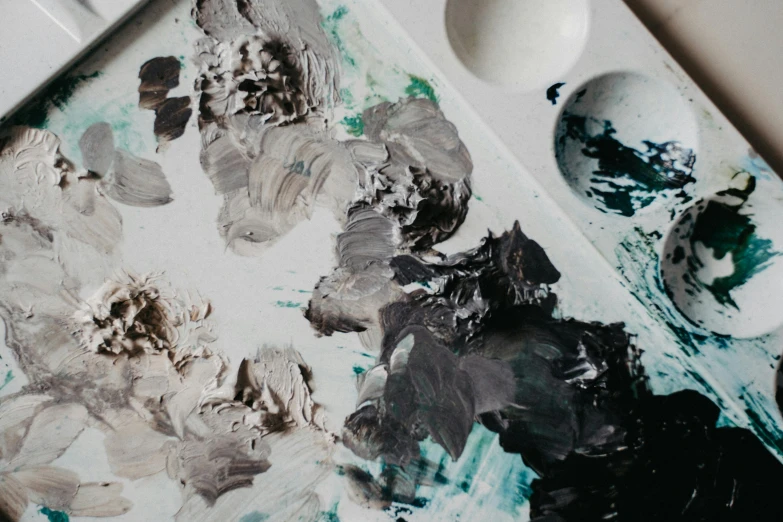 a close up of a painting on a table, inspired by Kyffin Williams, trending on pexels, silver palette, dirty colours, an artistic pose, palettes