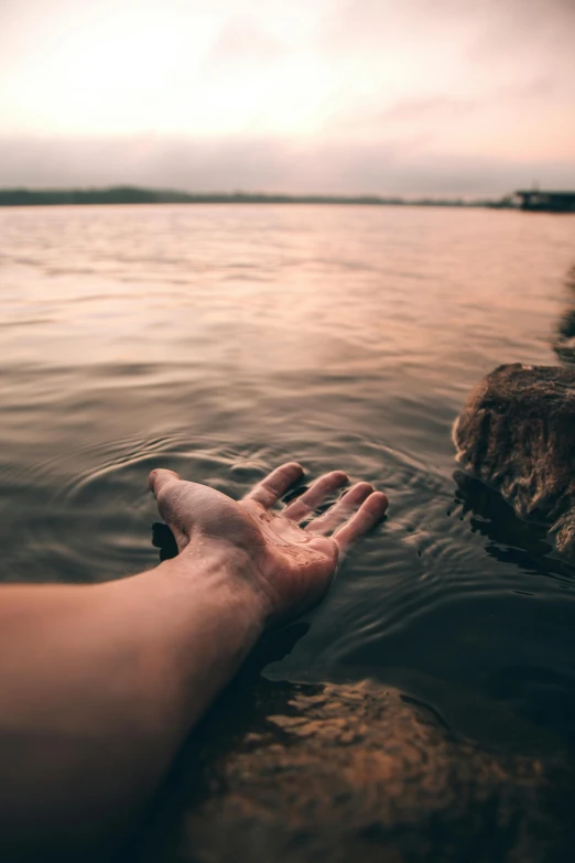 a person's hand reaching for a rock in the water, inspired by Elsa Bleda, unsplash, romanticism, paul barson, late summer evening, people drowning, uncropped