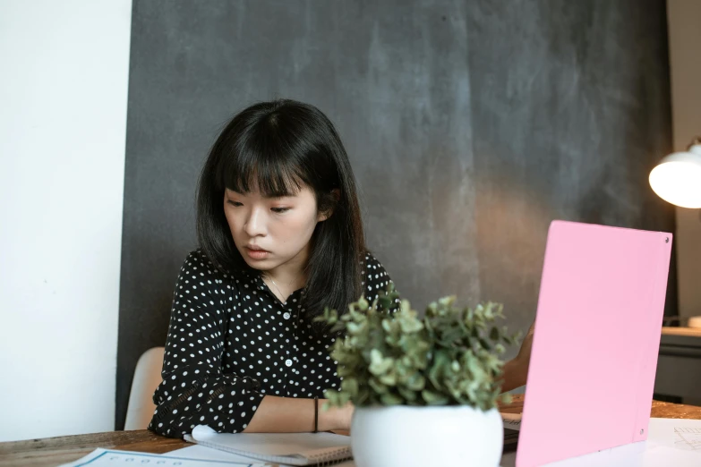 a woman sitting at a table in front of a laptop computer, by Jang Seung-eop, trending on pexels, pink and black, school class, background image, asian descent