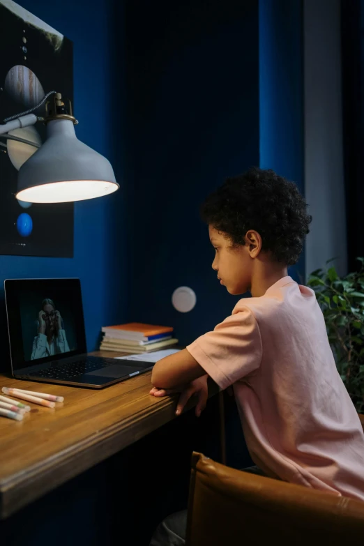 a little girl sitting at a desk with a laptop, a picture, by Everett Warner, pexels, oled lights in corners, black teenage boy, youtube thumbnail, ignant