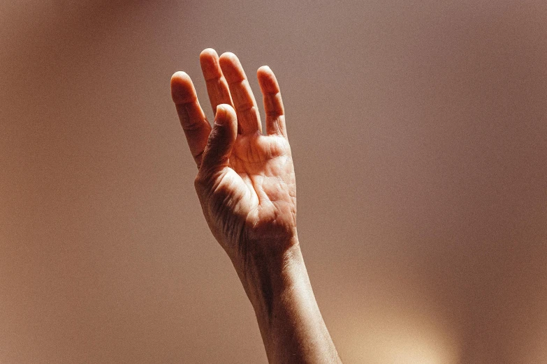 a person holding their hand up in the air, trending on pexels, hyperrealism, soft light from the side, instagram post, warm shading, colour photograph