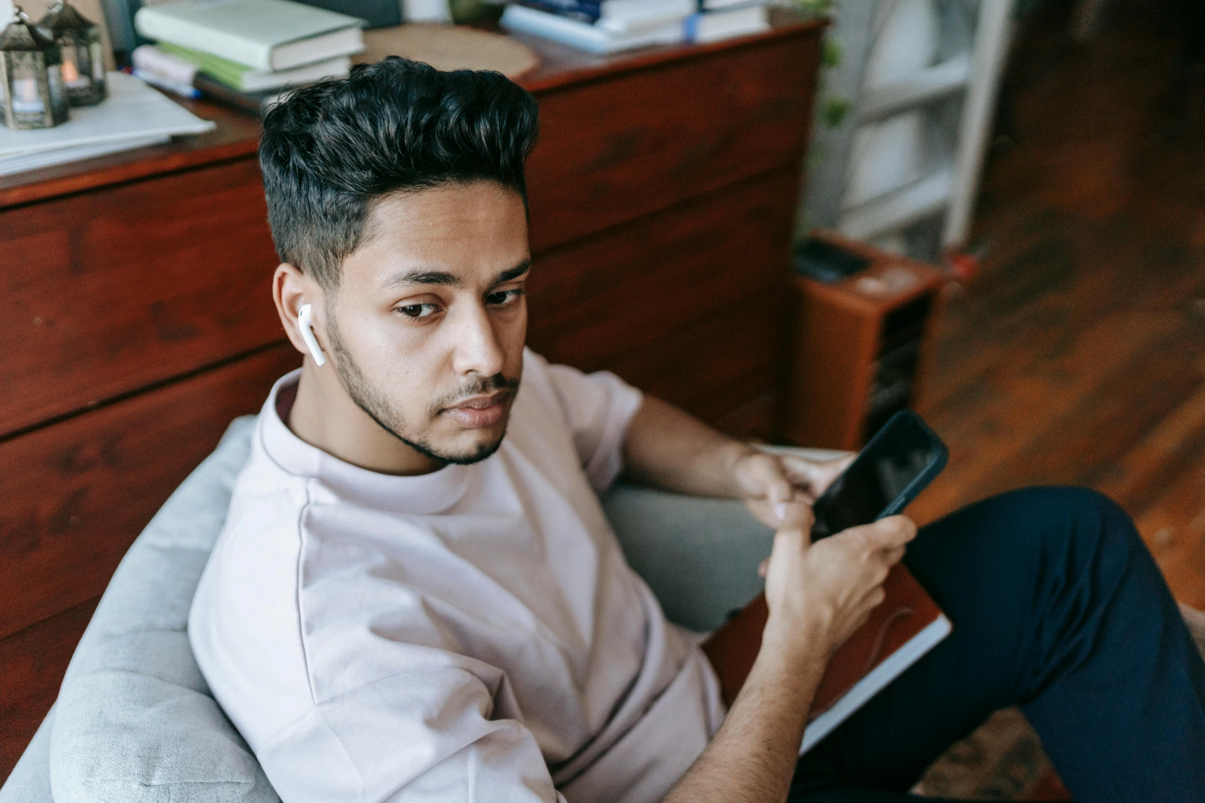 a man sitting in a chair holding a cell phone, a portrait, trending on pexels, middle eastern skin, trying to study, looking serious, youtube thumbnail