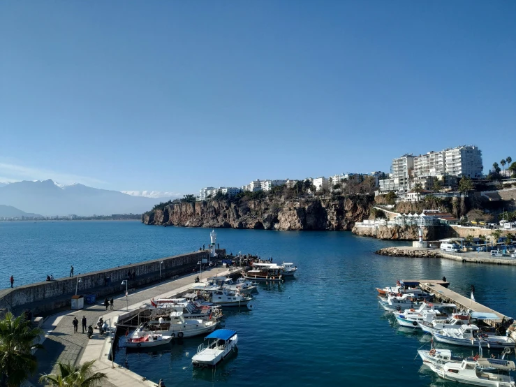 a large body of water filled with lots of boats, by Constantine Andreou, pexels contest winner, hurufiyya, cliff side, blue sky, mount olympus, harbour in background