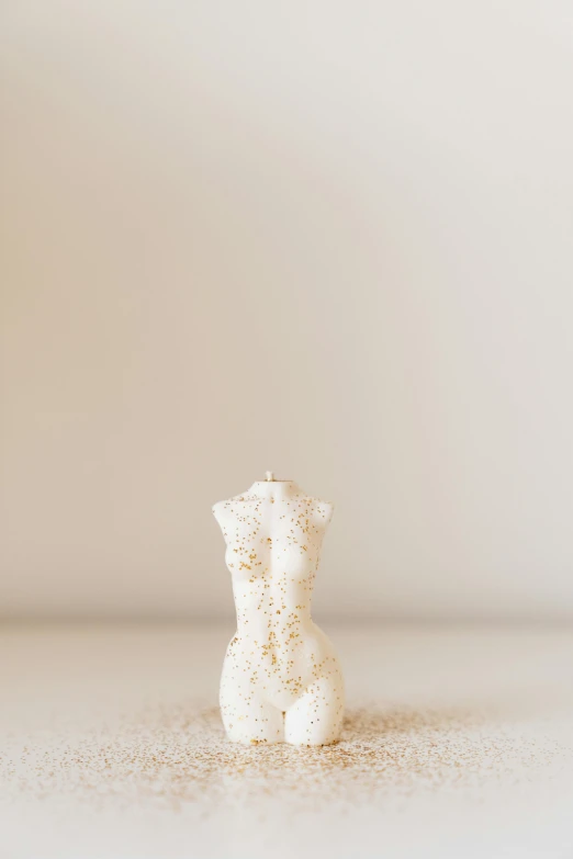 a white teddy bear sitting on top of a table, a marble sculpture, by Ellen Gallagher, unsplash, digital art, sand particles, body made out of macaroni, female body, white with gold accents