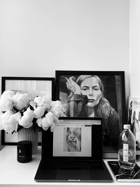 a laptop computer sitting on top of a white desk, a black and white photo, by Sara Saftleven, tumblr, fine art, harper's bazaar art, with flowers, portrait of kim wexler, framed in image