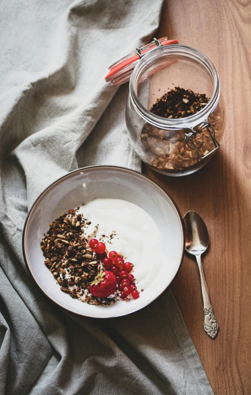 a bowl of cereal sitting on top of a wooden table, by Jan Tengnagel, pexels, yogurt, dwell, black forest, jars