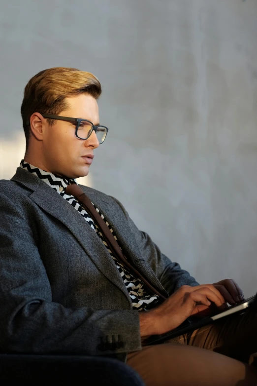 a man sitting in a chair using a laptop computer, inspired by Oskar Lüthy, trending on reddit, masculine appeal high fashion, very nerdy, nate berkus, profile image