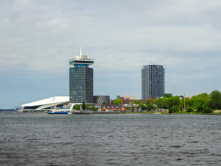 a large body of water with buildings in the background, by Daarken, brutalist buildings tower over, dutch masters, curvy build, 1km tall