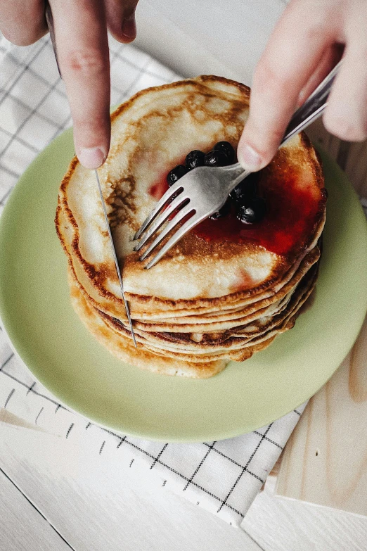 a person cutting a stack of pancakes with a fork, pexels contest winner, plates of fruit, solid bacgkround, green, small