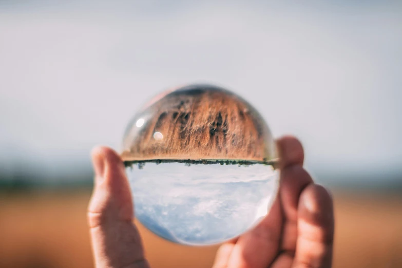 a person holding a crystal ball in their hands, unsplash, ultrawide landscape, heath clifford, made out of glass, instagram post