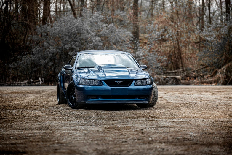 a blue car parked on top of a dirt field, a portrait, by Jeffrey Smith, unsplash, renaissance, mustang, 90's photo, front profile!!!!, nice slight overcast weather