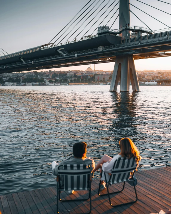 two people sitting in lawn chairs on a dock, pexels contest winner, renaissance, istanbul, under bridge, very romantic, male and female