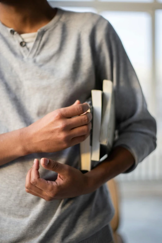 a close up of a person holding a book, stainless steel, elongated arms, grey and silver, ignant