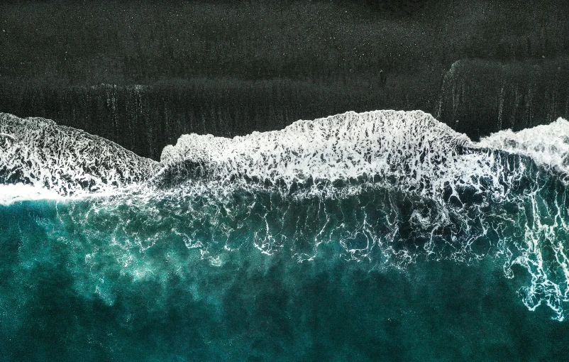 a person riding a surfboard on top of a wave, an album cover, unsplash contest winner, hurufiyya, black sand, aerial photo, teal landscape, frozen sea