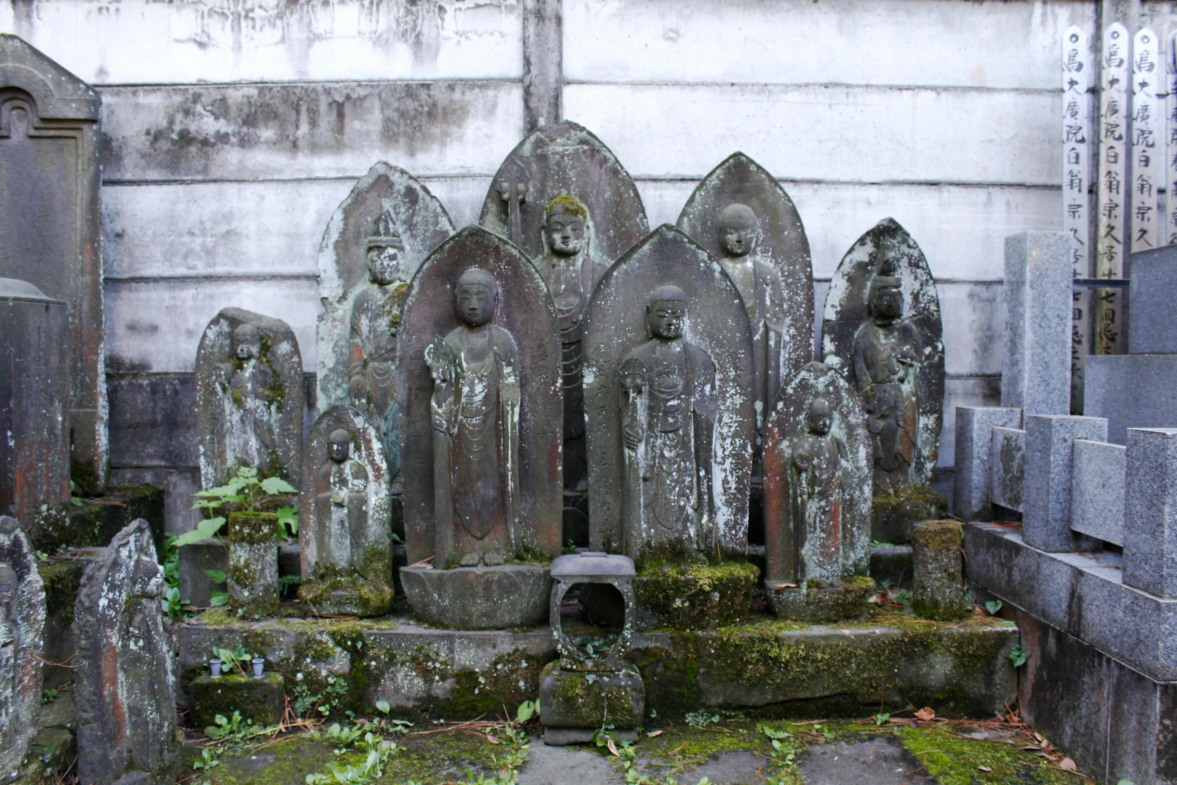 a group of statues sitting next to each other in a cemetery, inspired by Saneatsu Mushanokōji, mingei, gray, small stature, jakarta, fan favorite